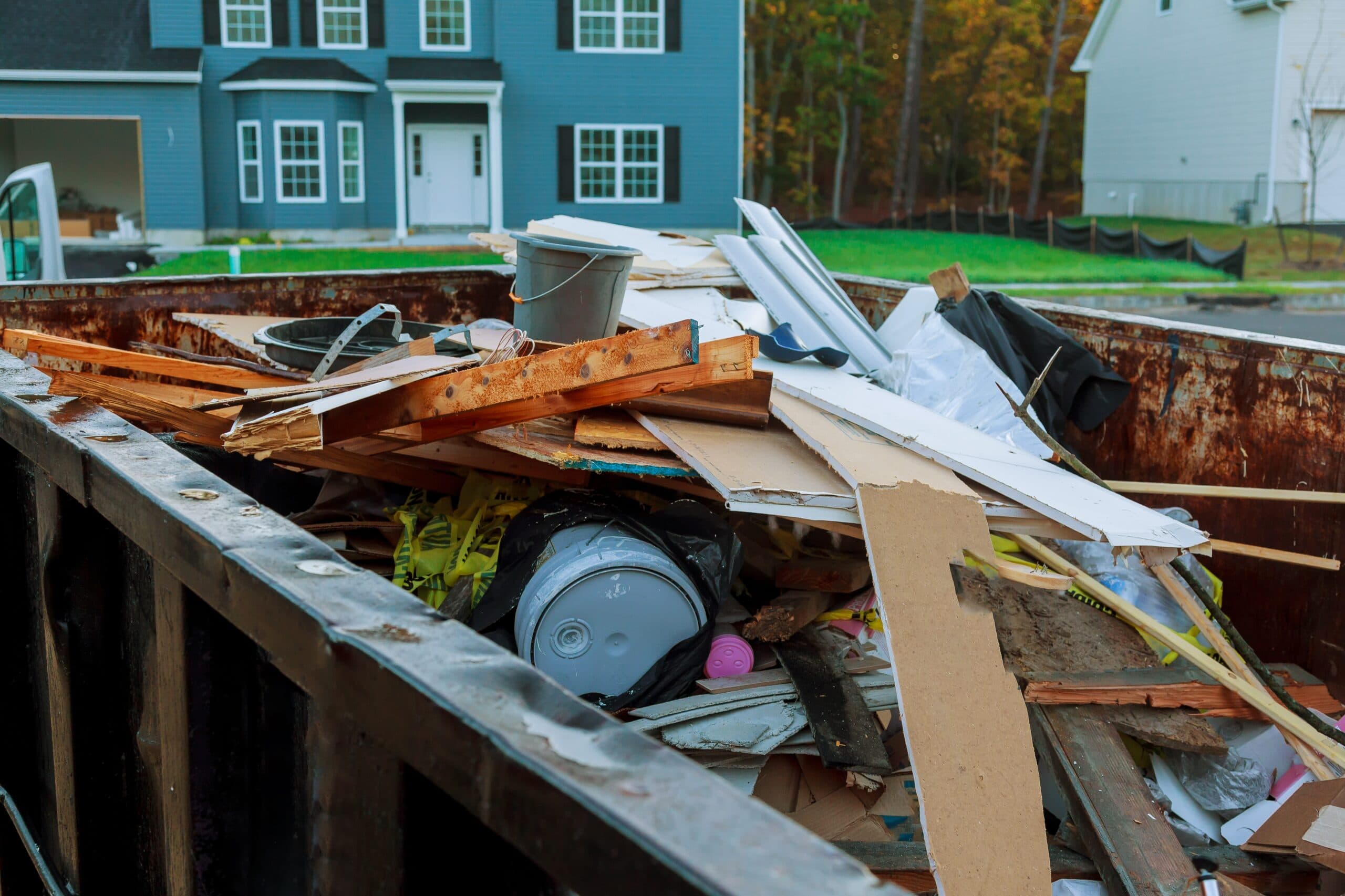 Construction debris loaded in a dumpster outside a house
